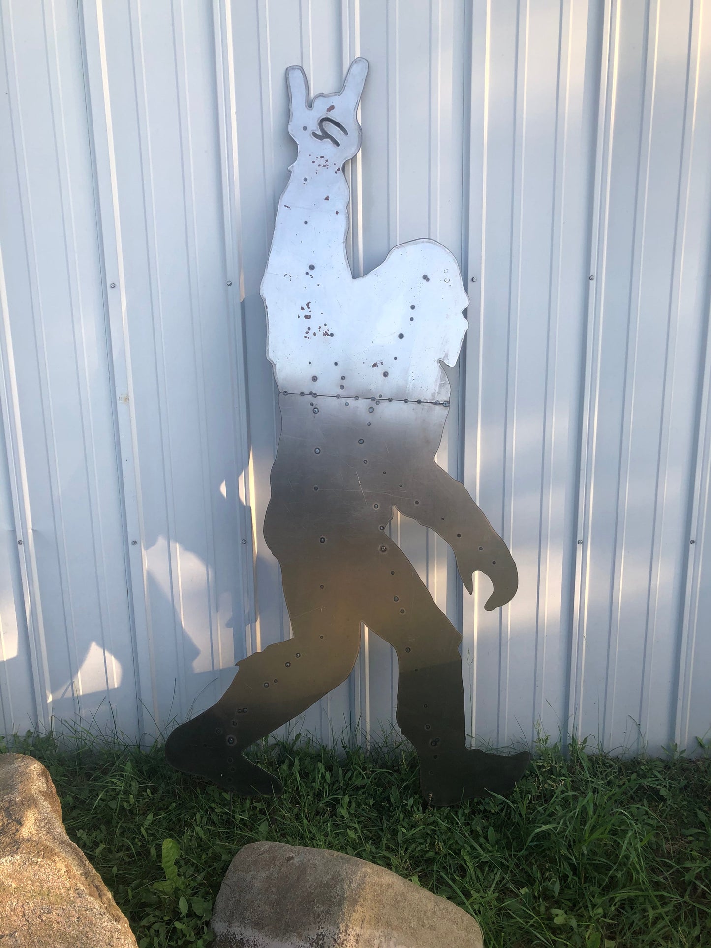 Metal wall art of a Sasquatch against a corrugated metal wall.