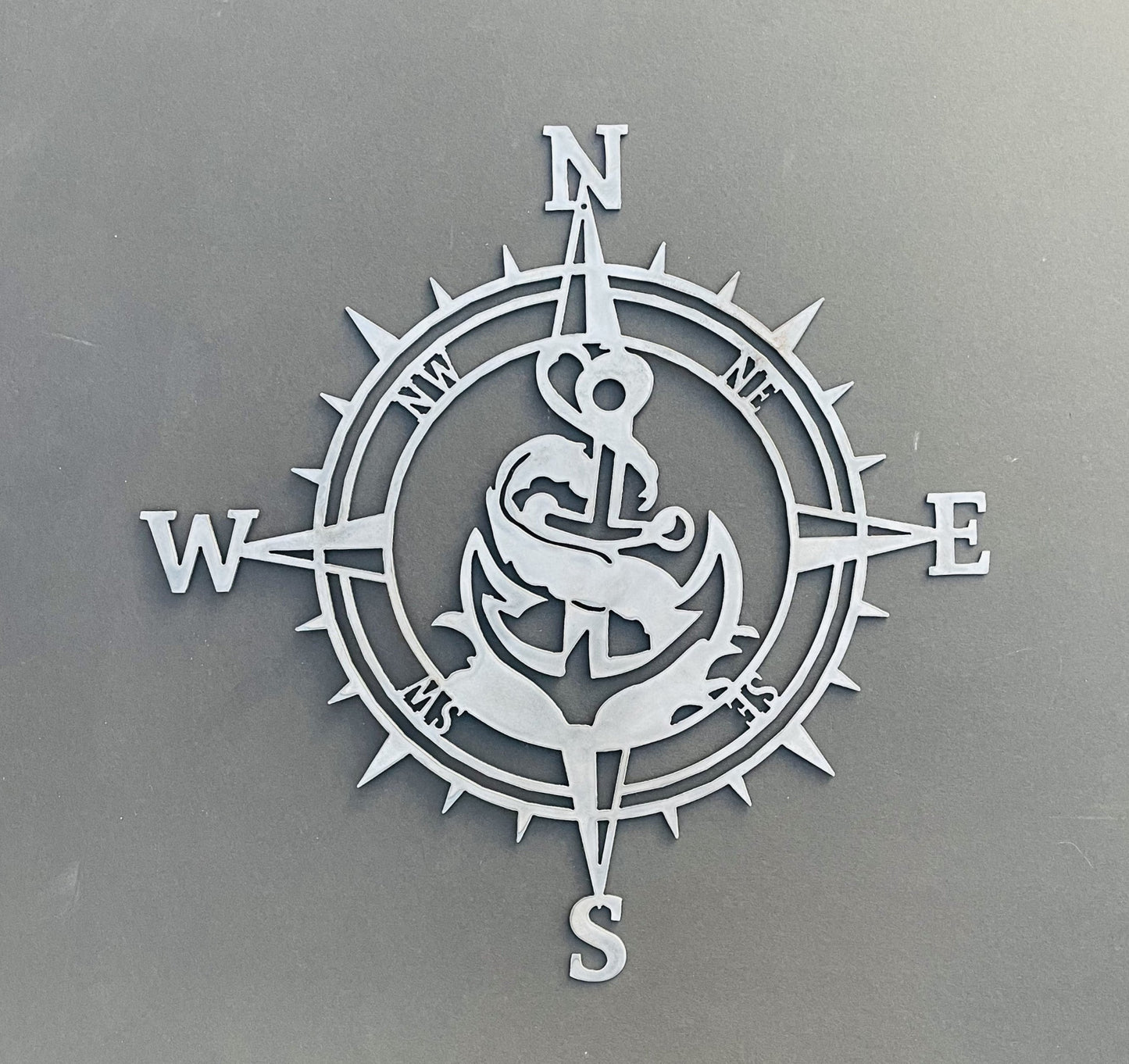 Decorative compass with anchor and waves design on a gray background