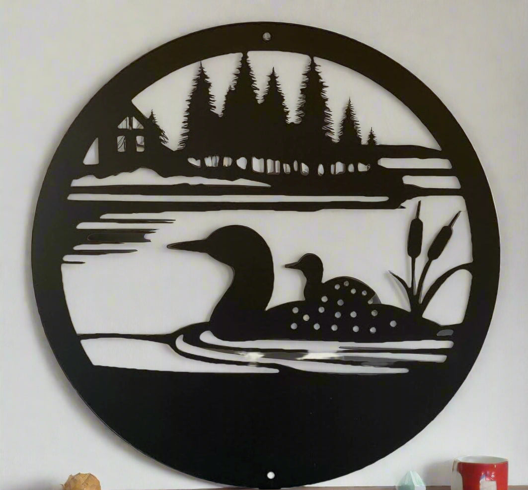 A round metal art piece with a lake, cattails, cabin, Loon, and offspring.
