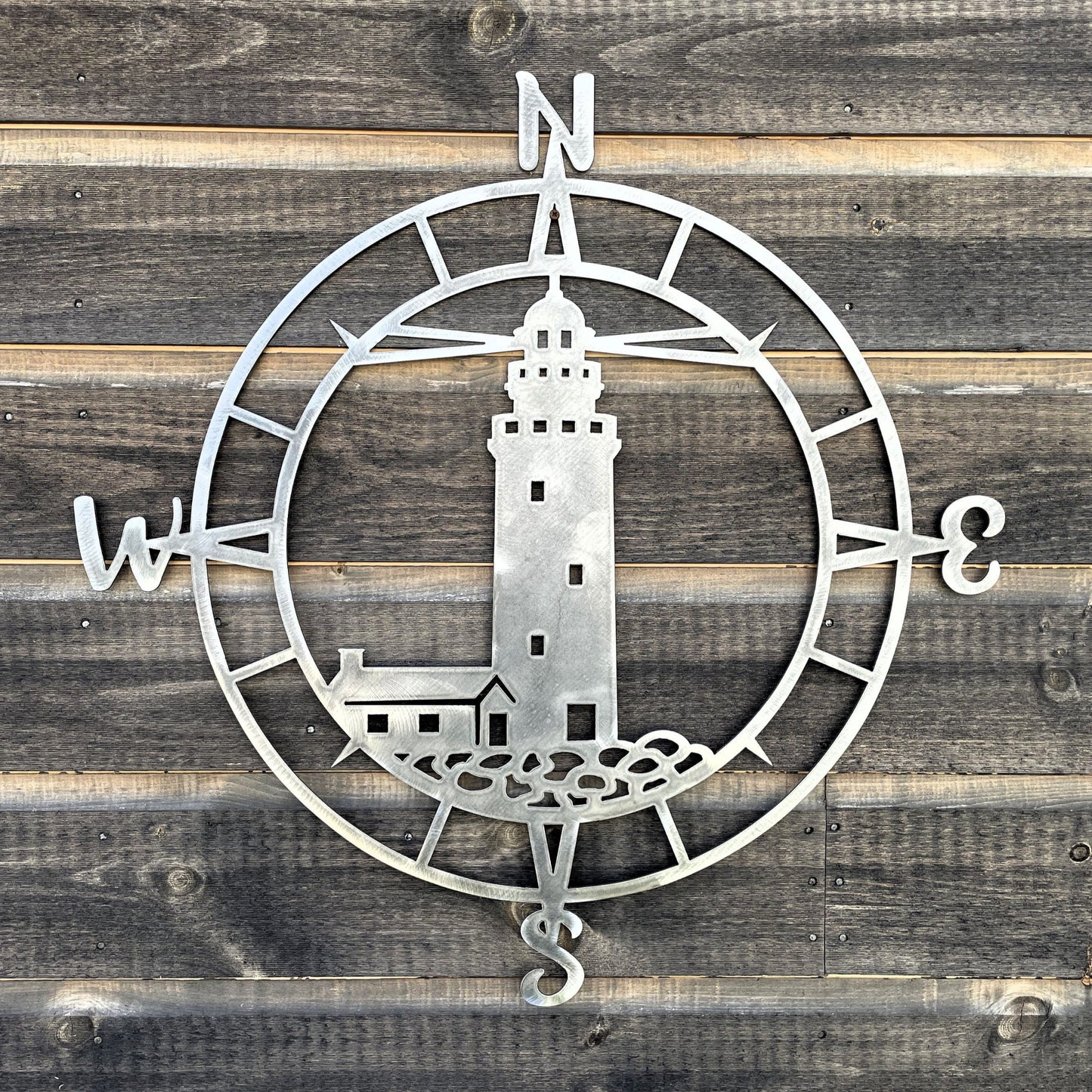 bare metal compass with a lighthouse scene