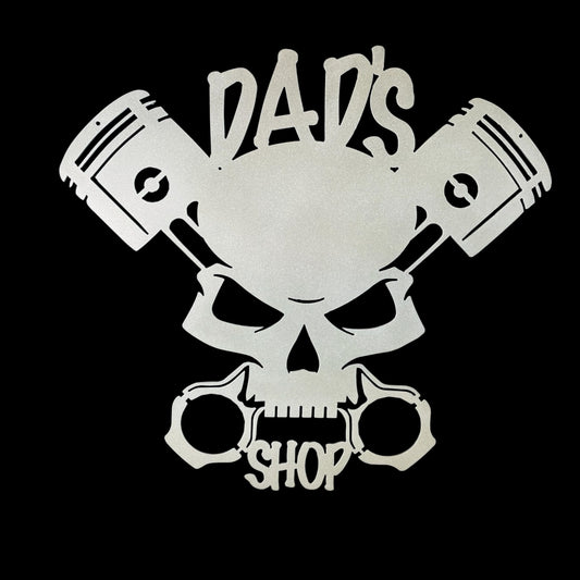 Skull with crossed pistons and 'Dad's Shop' text on a black background