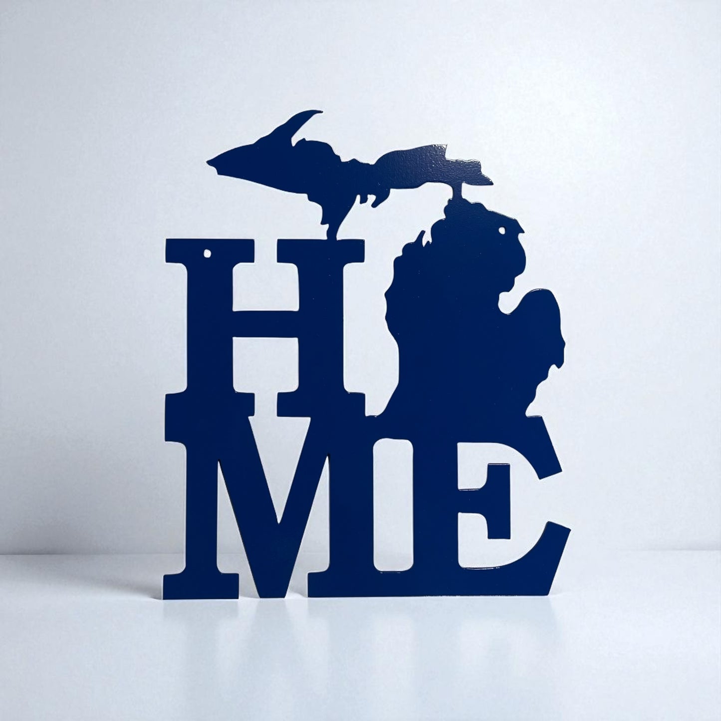 Blue metal decorative sign shaped like the state of Michigan with 'HOME' text on a white background