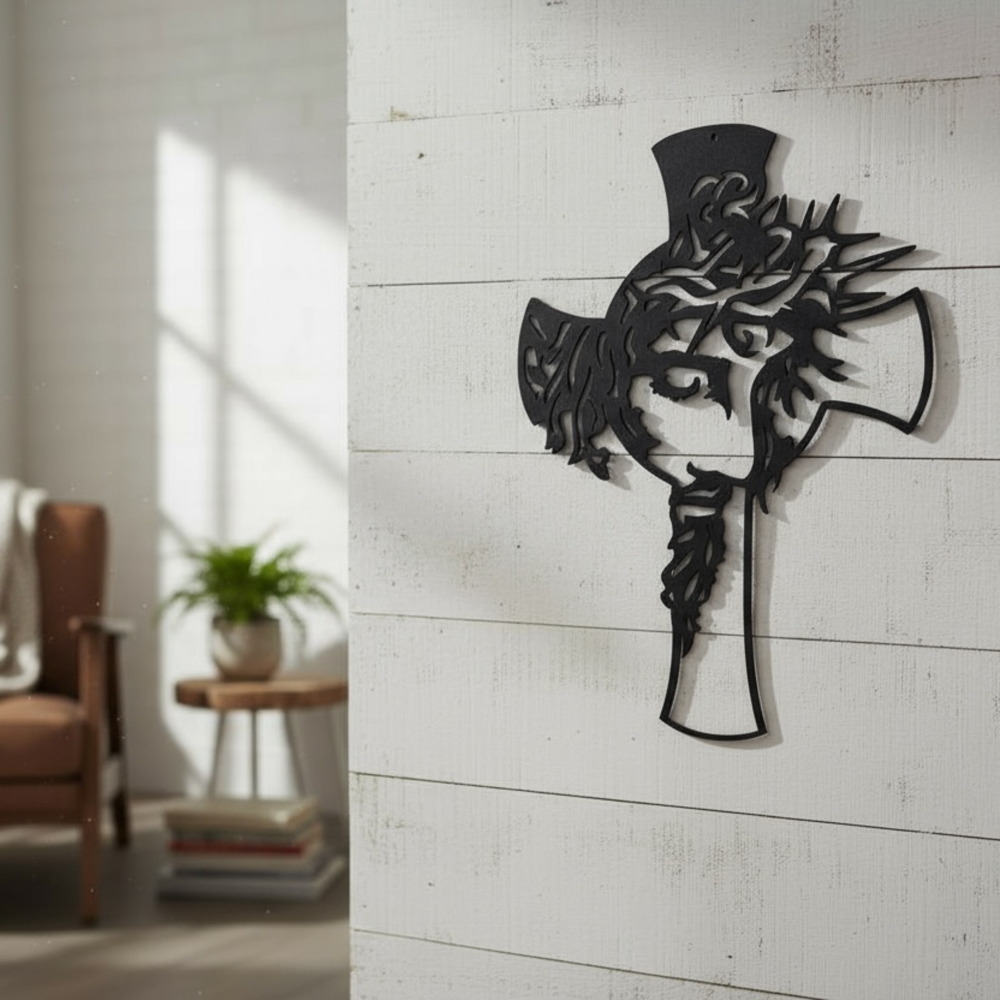 Decorative wall art of the face of Jesus within a cross on a white wall in a room with a chair and plant.