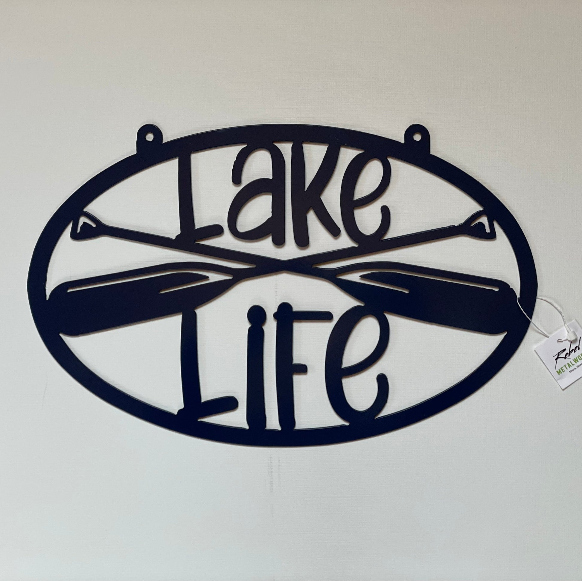 Decorative metal wall art with 'Lake Life' and crossed canoes on a white background