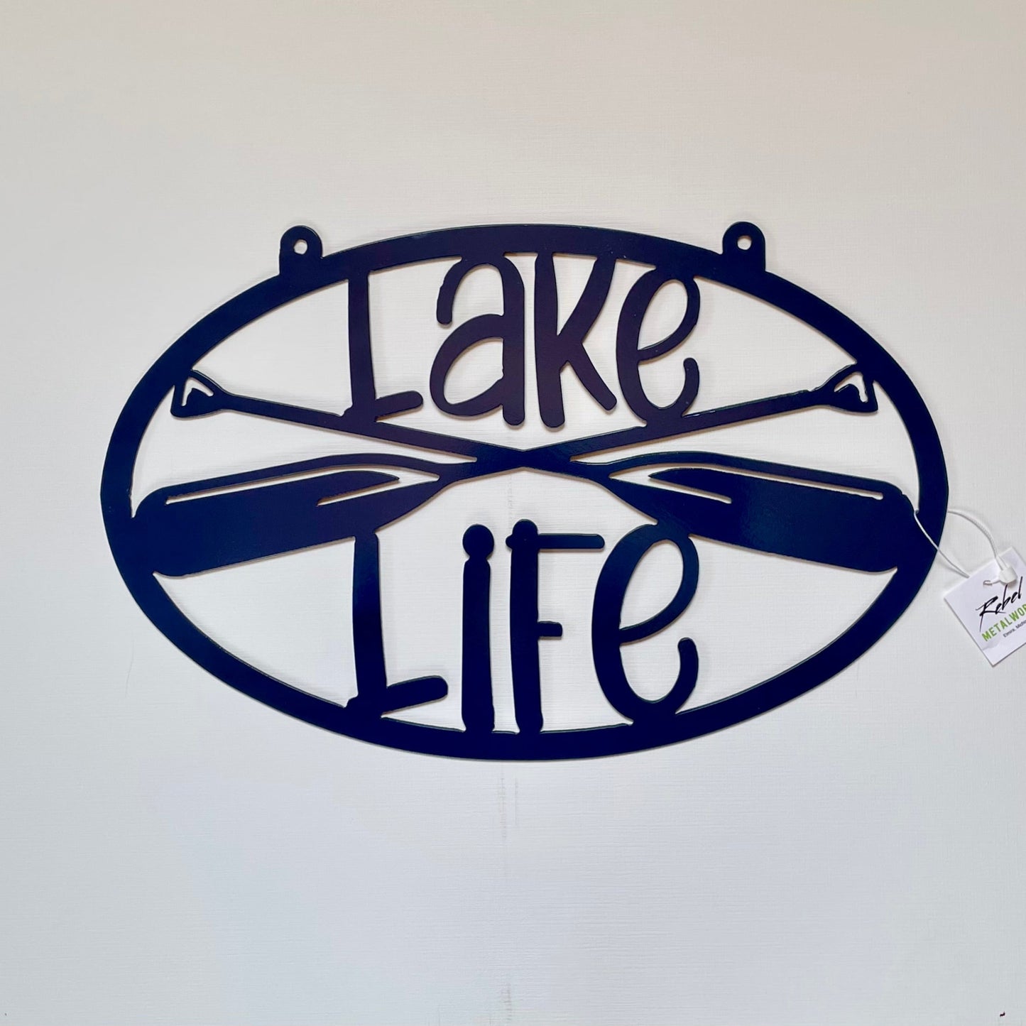 Decorative metal sign with 'Lake Life' text and oar designs on a white background