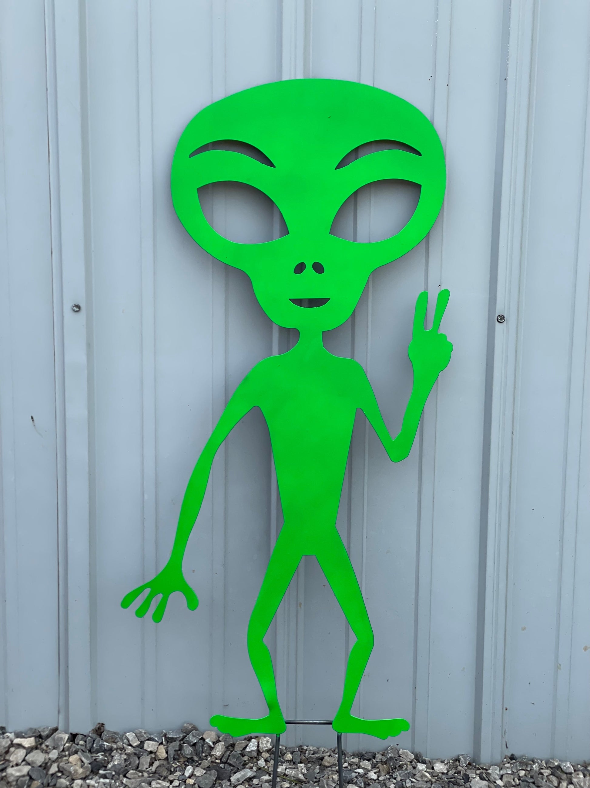 Alien green Martian holding up a peace sign.