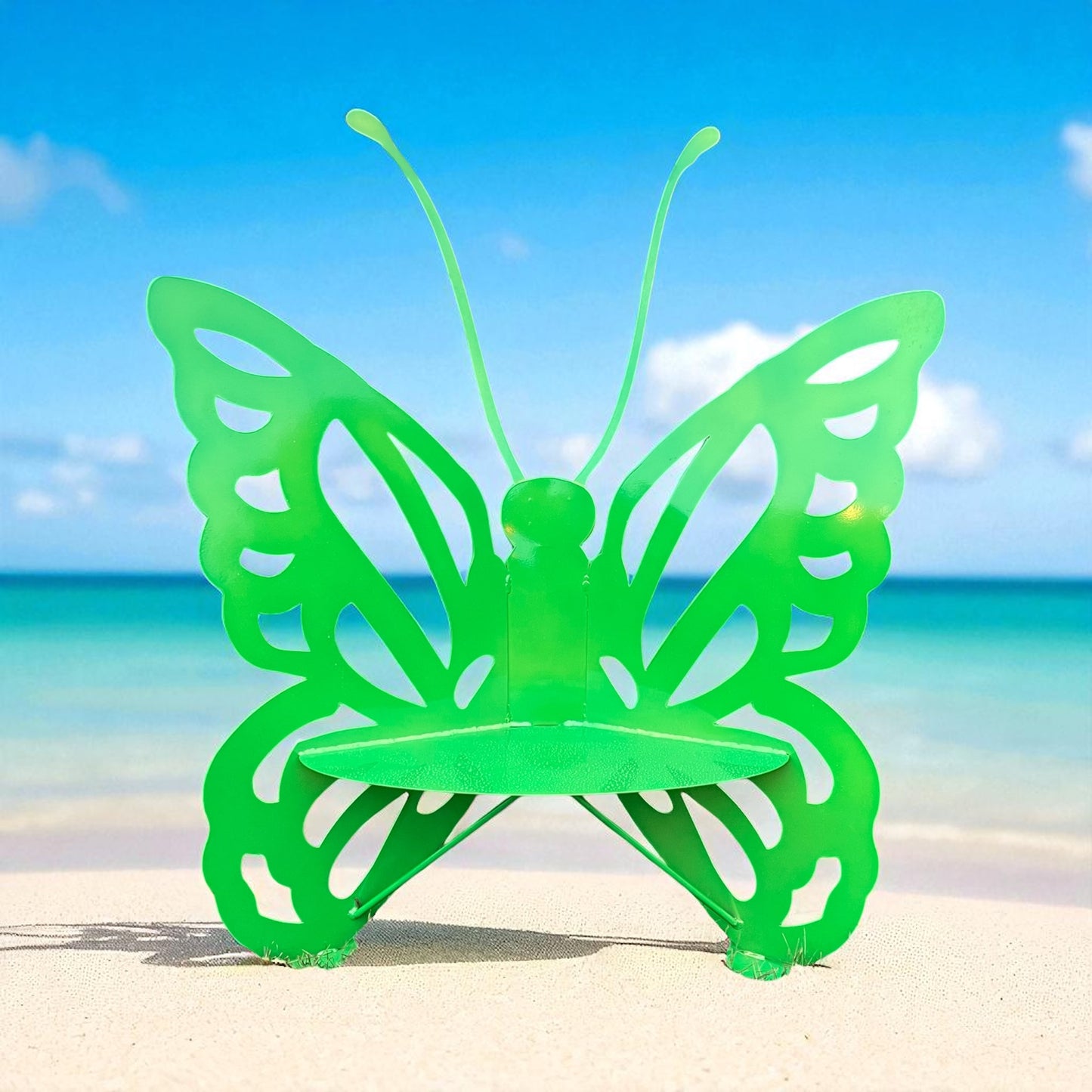 Green butterfly-shaped chair on a beach with blue sky and ocean in the background