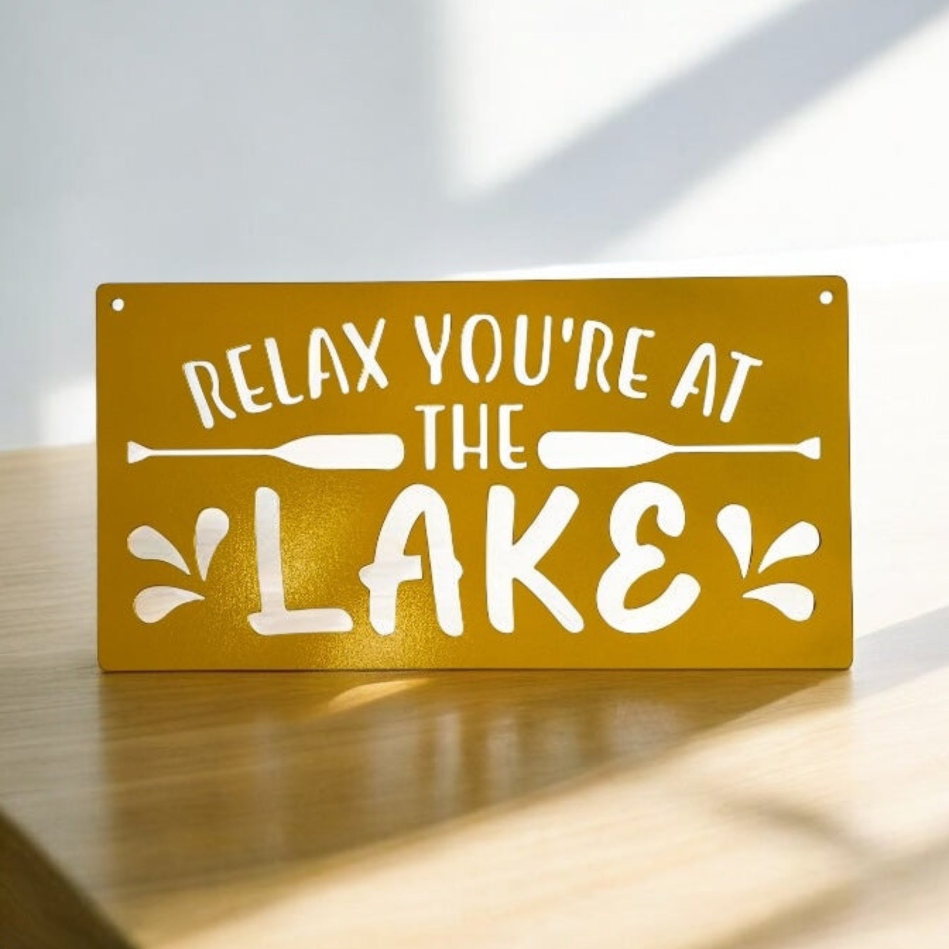 Yellow metal sign with Relax you're at the lake wording and oar graphics and details