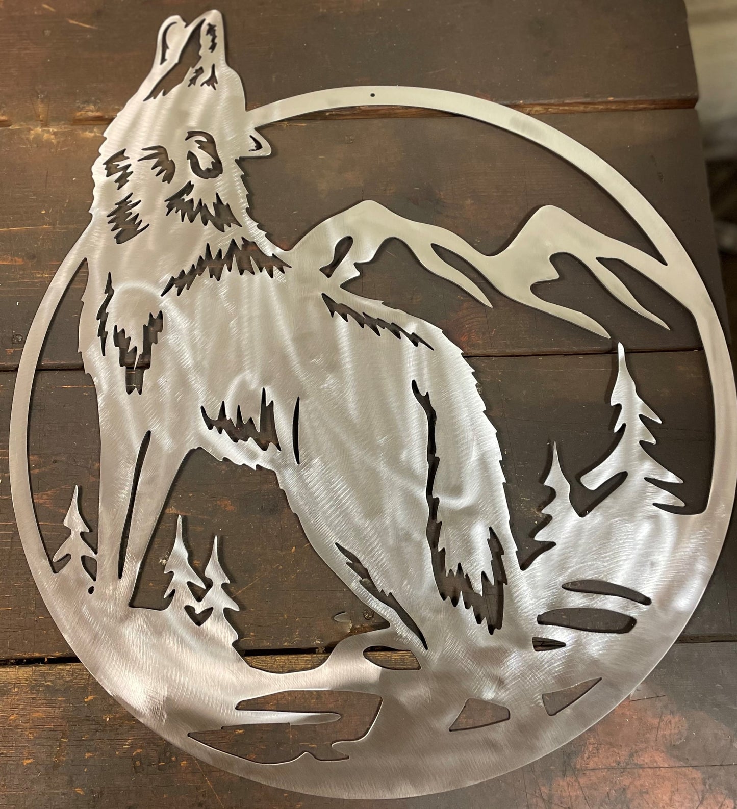 polished steel wall art with howling amongst trees and moutains.