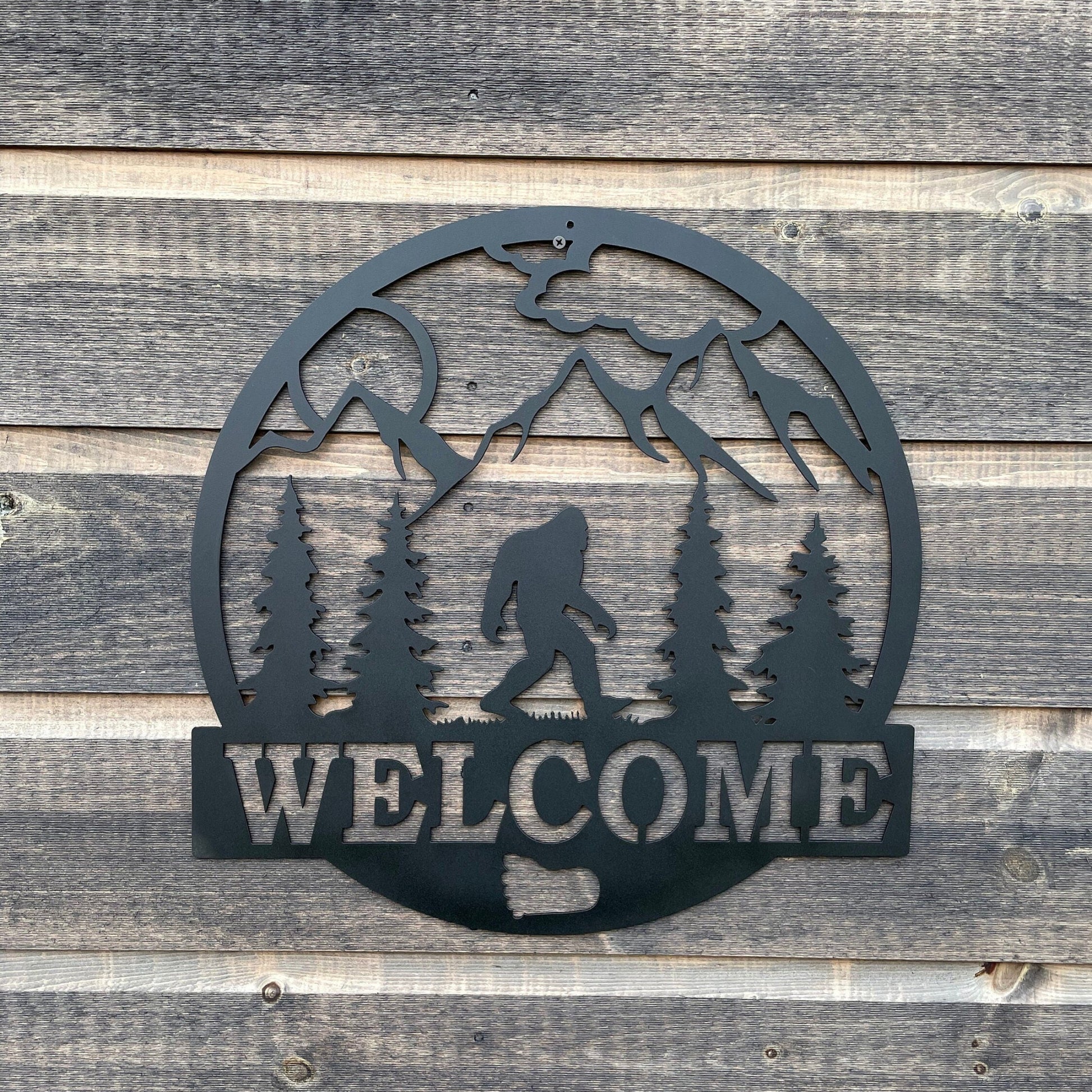 Bigfoot welcome sign with trees, mountains and sunshine