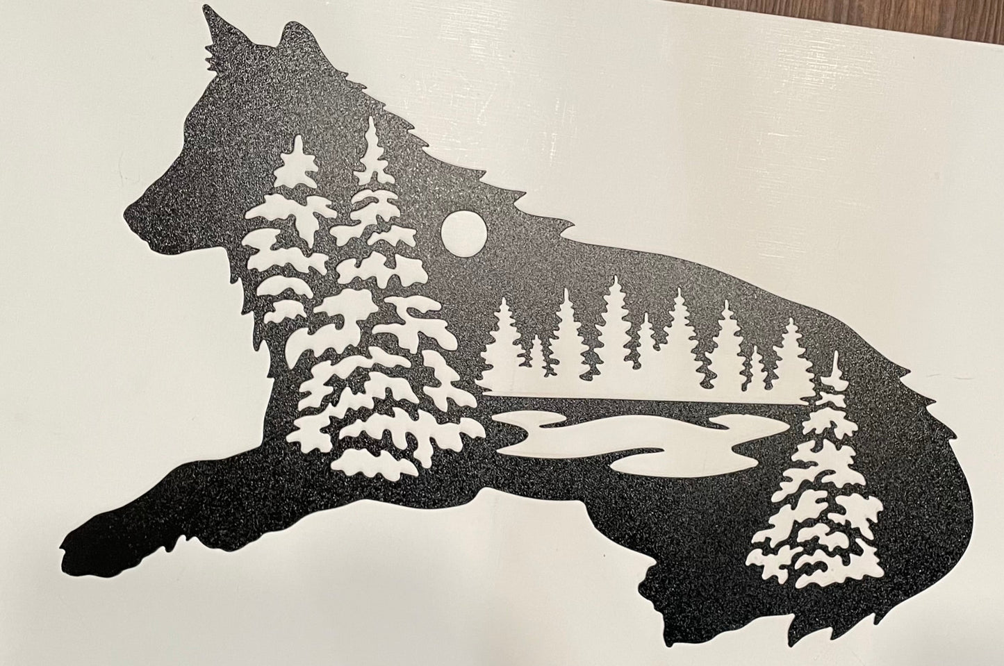 Silhouette of a wolf with a forest and moon design on a white background